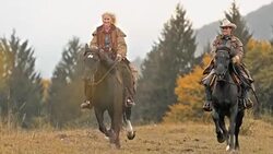 SLO MO Man and woman galloping across meadow on horses Stock Footage