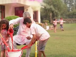 Senior man playing holi festival with his grandchildren in a lawn  Stock Footage