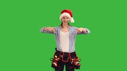 slender young woman construction worker in a cap of Santa Claus shows a copy space  on a green background Stock Footage