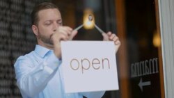 Small business owner hangs Open sign on door Stock Footage