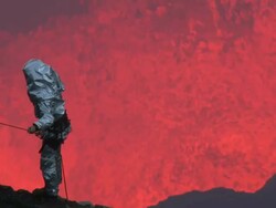 Volcanologist stands on cliff with large eruption of lava behind, Marum Volcano, Ambrym Island, Vanuatu Stock Footage
