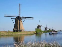 WS Shot of boat passing through river in front of  Windmills of Kinderdijk at UNESCO World Heritage Site / South Holland, Netherlands Stock Footage