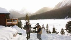 Playful couple enjoying snowball fight snowy mountain cabin Stock Footage