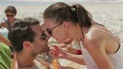 Young couple applying sunscreen to noses on beach Stock Footage