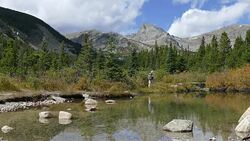 Backpacker man hiking Indian Peaks Wilderness Sawtooth Mountain wetlands Colorado Stock Footage