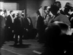 B/W 1963 Lee Harvey Oswald being led thru hallway lined with people / newsreel Stock Footage