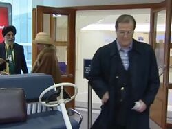 Sir Roger Moore with his wife shortly after heart problem diagnosis flies out of Heathrow Stock Footage