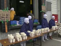 Aftermath of tsunami after magnitude 9 Tohoku earthquake, north east Japan, March 2011. People gather supplies at tofu factory in Osaki city after tsunami Stock Footage