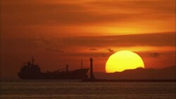 A giant sun sinks below the horizon near a silhouetted ship on Manila Bay. Stock Footage