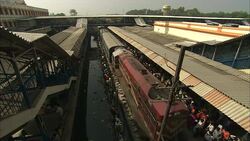 Commuters wait on a crowded train platform near filthy water in India. Stock Footage