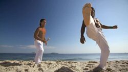 Capoeira fighter on Ipanema Beach kicks sand and claps hands together at camera Stock Footage