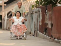 Asian senior man pushing him disabled wife on wheelchair Stock Footage