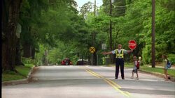 A crossing guard holds stop sign as children cross a street on their way to school. Stock Footage