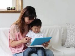 A mother and her son playing game on a tablet together in the livingroom Stock Footage