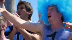 MS Football fan wearing wig and body paint cheering and high fiving with crowd during game Stock Footage