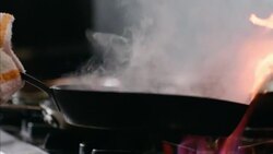 Restaurant chef shakes skillet of scallops over flaming stove top in slow motion Stock Footage