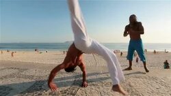 Brazilian capoeira artist kicks and flips for camera on Ipanema boardwalk Stock Footage