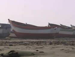 "L-R pan of colourful wooden boats sitting on sandy beach, men lying relaxing, Trujillo, Peru [PerÃƒÂº]" Stock Footage