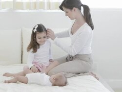 Caucasian mother on bed with baby and little girl Stock Footage