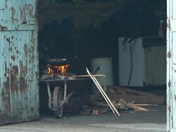 A fire burns in a wheelbarrow near a door with chipped paint in Buenos Aires. Stock Footage