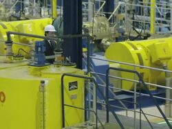 LS HA two businessmen walking on gangway through compressor and pumping hall of water treatment plant; entering frame left, pausing briefly to survey the installation and exit frame right, RED R3D 4K Stock Footage