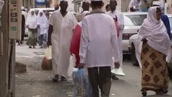 A Muslim man and woman walk through a crowded street market in Mecca, Saudi Arabia. Stock Footage