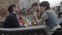 Group of friends sit and talk over coffee at outdoor caf_ Stock Footage