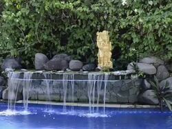 MS View of Hotel swimming pool with little waterfall and statue at Asia / Candi, Dasa Bali, Indonesia Stock Footage