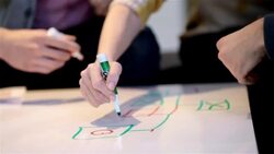 Creative young business people write on white-board table in large corporate office common area (detail) Stock Footage