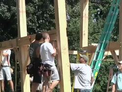 WS TU ZO Carpenters and crane operator slowly moving part of structure into place during framing of an energy efficient post / Grass Lake, Michigan, USA  Stock Footage