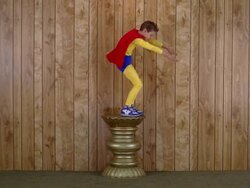 Wide shot boy in super hero costume standing on pedestal and pretending to fly Stock Footage