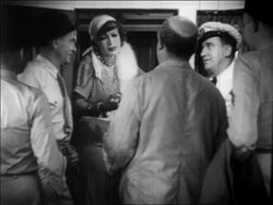 B/W 1932 zoom out woman (Joan Crawford) leaning in doorway with cigarette + talking to men / feature Stock Footage