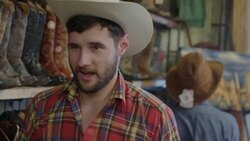 Young man in cowboy hat has fake shootout with friend in Western store and drops to the floor as if shot Stock Footage