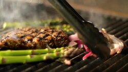 Tongs adjust onions on a grill. Stock Footage