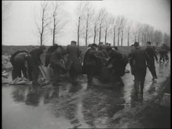 Flood waters rush around a windmill and relief workers fill sandbags during the North Sea storms and floods in Holland. News Clip