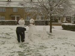 MS man making large snowmen, United Kingdom Stock Footage