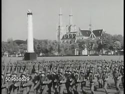 1940: EAST ASIA PREPARES: Dutch Naval officers in map room, maps on table. Soldiers marching w/ Gereja Katedral Jakarta (cathedral) BG. Soldiers riding bicycles on street. Soldiers in jungle war maneuvers, firing rifle, setting up antiaircraft guns. Instructional Video