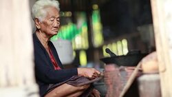 Pitiable Senior asian woman Sitting a Cooking Food on Mud Stove at Home Stock Footage