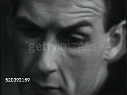 1935: DRAMATIZATION: People reading newspaper. CU Newspaper w/ Alexei Stakhanov photo. VS People reading. VO changing to Stalin VO (not real)about people working according to ability, receives according to what has been produced. People outside house. Instructional Video