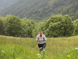 Woman hikes up through mountain meadow, flowers  Stock Footage