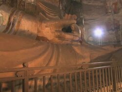 MS PAN TU Shot of giant Buddha sutra carving in cave and monk kneeling and praying in front of it at Yungang Grottoes / Datong, Shanxi Province, China Stock Footage