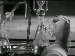 1952: SCREENING URANIUM: Middle-aged male in lab coat working in laboratory, adjusting machine, CU Male hand turning valve on beaker, dark liquid rising in tube. Cold War. Instructional Video