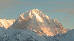 A band of clouds drifts past a rugged, snowy summit. Stock Footage