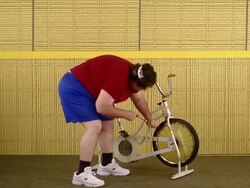 Medium shot fat man using air pump and kicking exercise bicycle over w/frustration Stock Footage