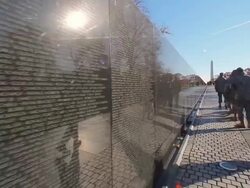 A handheld shot of the back of a group of soldiers walking by a wall near the Washington Monument. Stock Footage