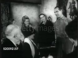 1935: DRAMATIZATION: EXT Village home of Alexei Stakhanov. INT Home w/ photographer taking photo of male talking , smiling, people celebrating, opening presents. People outside looking at car (gift from Stalin)  Note: This man is NOT Alexei Stakhanov Instructional Video