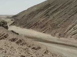 A low level river winds through the scarred rock faces of the Moroccan mountains. Stock Footage
