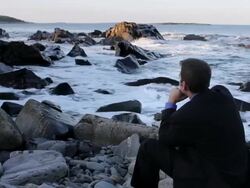 MS Man sitting on rocks looking out over ocean / Portland, ME, United States Stock Footage