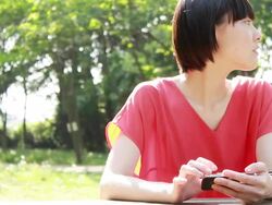 MS Shot of young woman using smartphone in park / Nakano, Tokyo, Japan Stock Footage