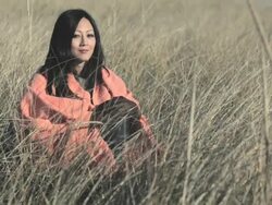 Mature woman in marram grass, wrapped in blanket Stock Footage